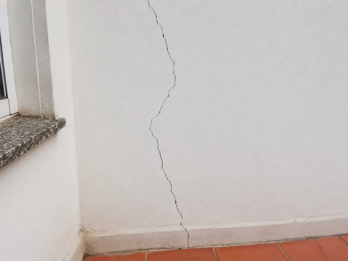 Rachadura na parede vertical e contínua, do teto ao rodapé, ao lado de janela com peitoril de granito